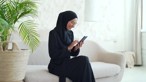 Smiling Woman Using Mobile Phone on Couch Indoors