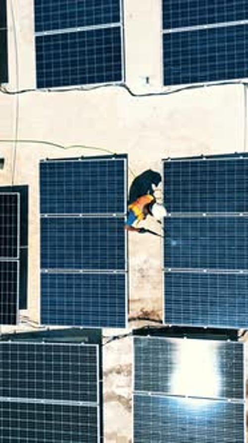 Vue aérienne d'un travailleur nettoyant des panneaux solaires sur un toit, au Honduras.