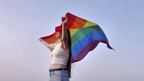 Young Woman Proudly Waving Pride Flag Outdoors