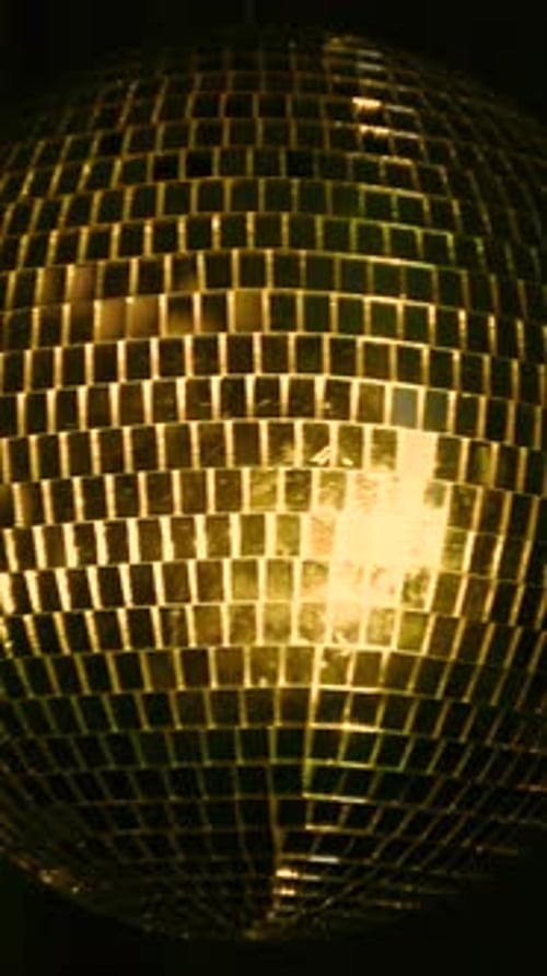 Dazzling disco ball reflects colorful lights. Vertical