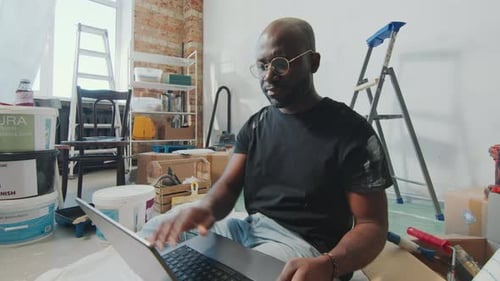 Man Using Laptop While Renovating Home