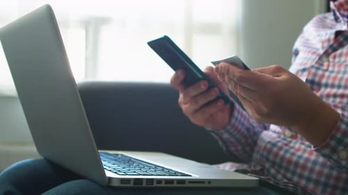 Person Using Laptop with Credit Card and Smartphone