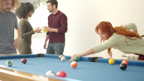 Woman Hitting a Ball Playing Pool with Friends at Home