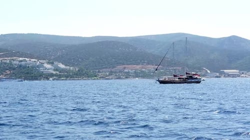 Blue Seascape with Sail Boat Blue Sky and Mountains Horizon Line Little Wave at Sea Smooth