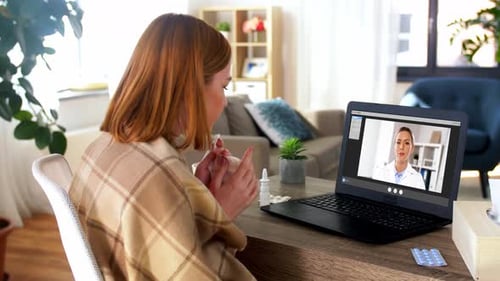 Woman having telemedicine consultation, sitting at table indoors