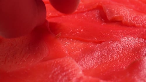 Hand takes red pickled ginger for sushi rolls from plate. Background for restaurant, bars, public