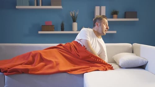 Man in bed looking around with fear and anxiety.