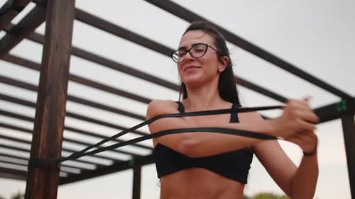 Woman Exercising With Resistance Band Under Wooden Structure