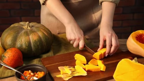 Woman Preparing Pumpkin, Cutting into Cubes on Board