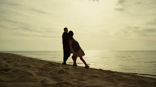 Family Enjoying Sunset on Beach. Happy Kid Girl Running Around Parents At