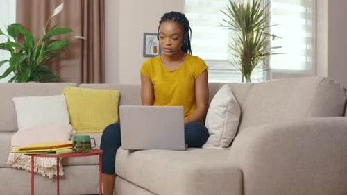 Woman in living room using laptop and headset