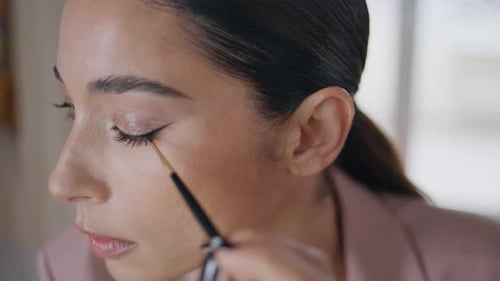Closeup Woman Applying Eyeliner Makeup at Room Interior. Visagiste Lady Face Drawing