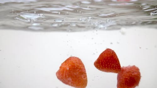 Fresh red strawberries floating on water surface, underwater shot