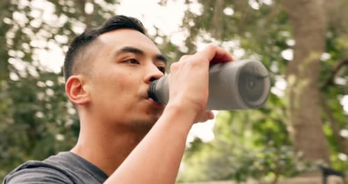 Drinking water, calm and outdoor man from China in nature feeling peace after hydrate drink