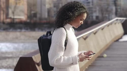 Young Woman Walking and Using Smart Phone in Sunny Park 2024 Years