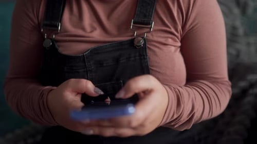 Focused Woman in Casual Attire Uses Mobile Phone Concentrated Typing Texting on Smartphone Screen