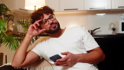 Man with Curly Hair Using Phone and Resting
