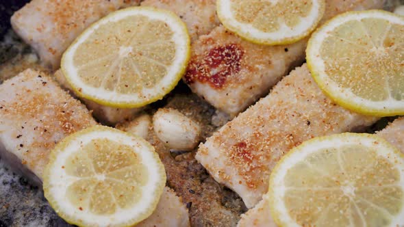 Hake Fillets Cook in a Pan with Garlic Lemon Slices and a Buttery Sauce ...