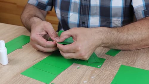 Man Assembling Green Paper Box at Table Close Up