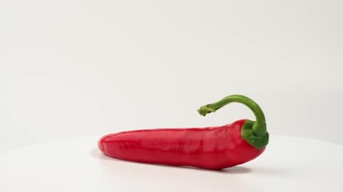 Shiny Red Chili Pepper Rotating on White Table