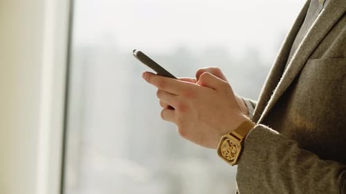 Person Using Mobile Phone near Urban Window