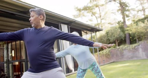 Focused diverse senior couple practicing yoga in garden