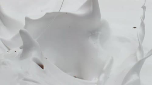 Chunks of Chocolate Fall Into Creamy White Liquid