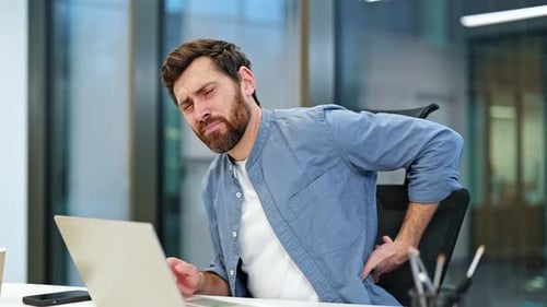Businessman Working at Computer Experiences Back Pain in Office