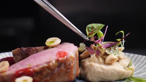 Chef Garnishing Gourmet Meat Dish with Micro Greens