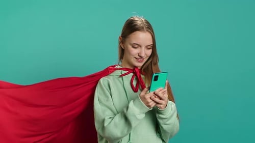 Young Girl Wearing Superhero Costume Texting Friends Using Smartphone