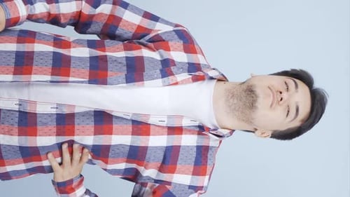 Smiling Young Adult Buttoning Plaid Shirt