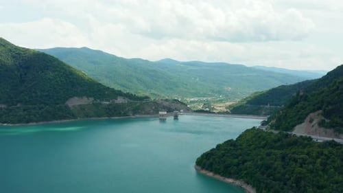 Luftpanorama auf das Gebirgstal, den türkisfarbenen See, umgeben von grünem, üppigem Wald und Bergen