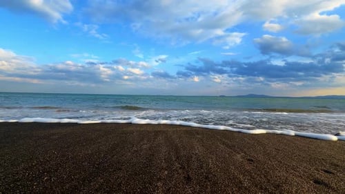 Las olas tocan suavemente la costa en un lugar costero al final de la tarde.