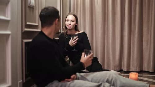 Couple Enjoying Wine Sitting on Floor Indoors