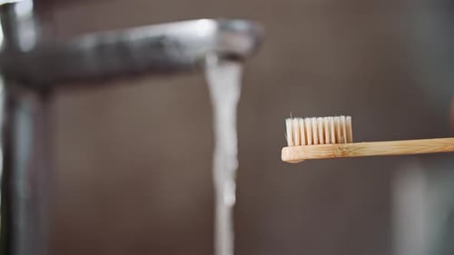 Applying Toothpaste to Toothbrush in Bathroom Close Up