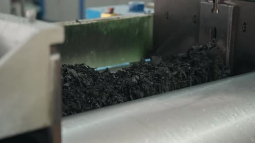 Recycled shredded rubber being processed in a factory