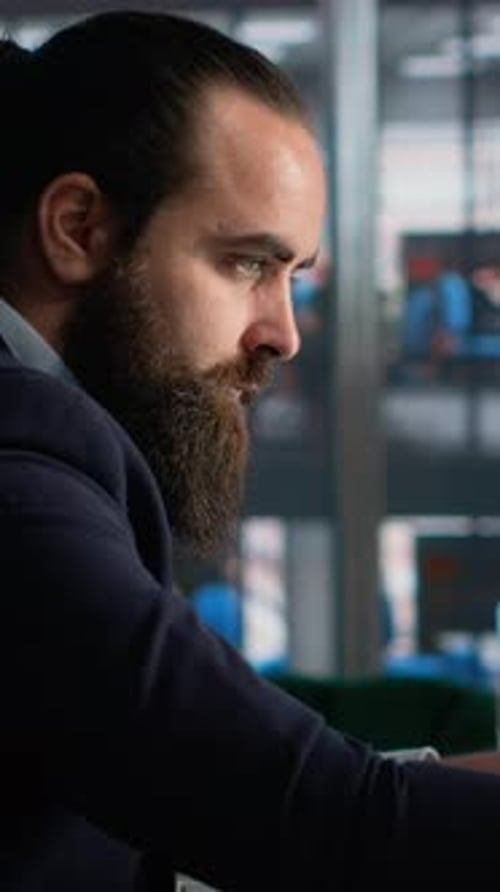 Serious bearded man in suit looking at computer