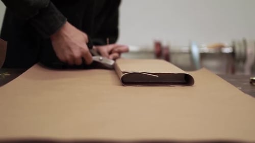 Hands Cutting Brown Kraft Paper with Scissors