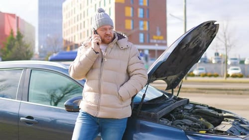 Man Talking on Phone Near Broken Down Car