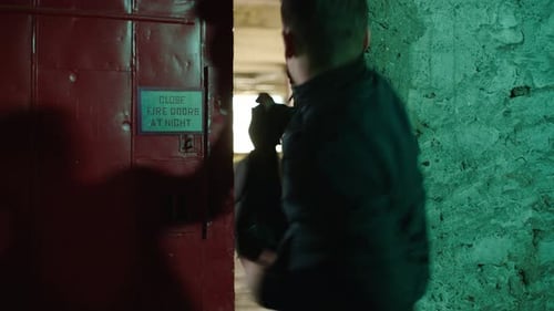 Un homme en fuite franchissant les portes d'un ancien entrepôt maussade