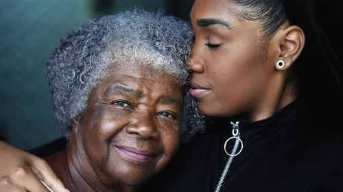 Smiling Woman Kisses Grandmother on Forehead, Close Up