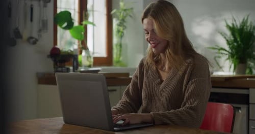 Smiling Woman Working on Laptop in Kitchen