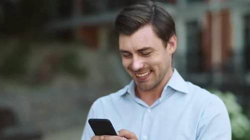 Close Up Smiling Man Writing Message on Mobile Phone Outdoor. Happy Businessman