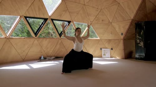 Une femme pratique le yoga en s'étirant de haut en bas dans un studio extérieur géométrique et serein, en se concentrant sur son esprit