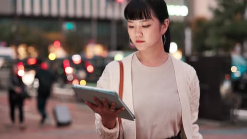 Business, tablet and walking with Japanese woman outdoor at city for break or email in evening