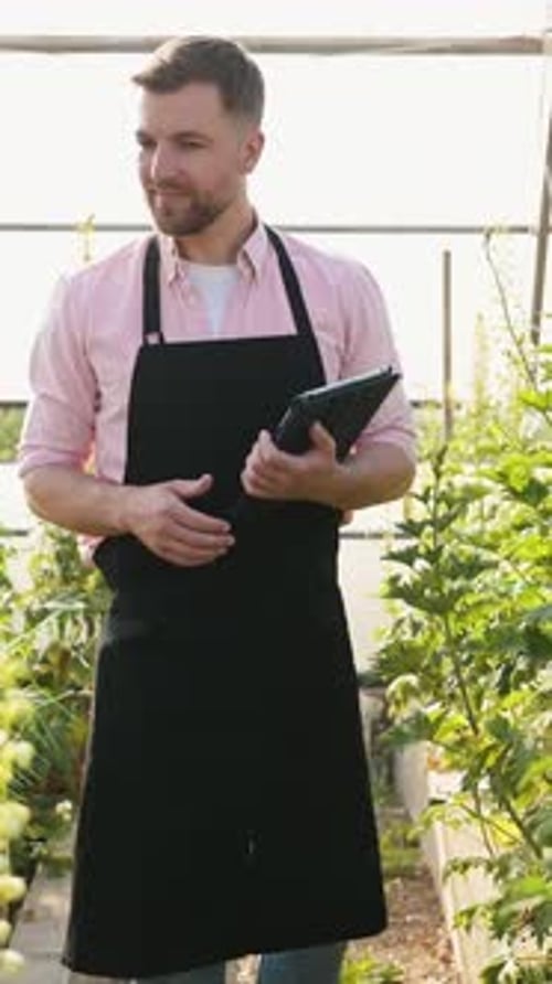 Agriculturalist Holding Tablet in Beautiful Greenhouse