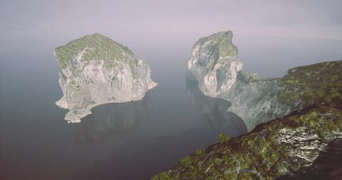 Rocky Cliffs Rise From Calm Waters at Daybreak Near a Quiet Coastline