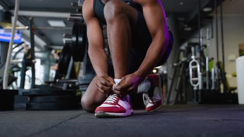 African American Sportsman Ties His Sneakers Close Up