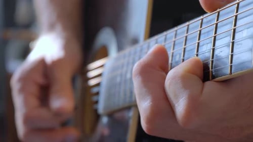 A Man Plays A Solo On An Acoustic Guitar Using A Pick