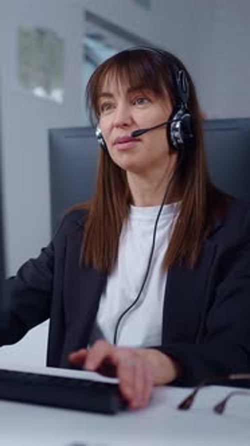 Professional Female Customer Support Agent Wearing Headset Working at Computer in Modern Office